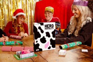 3 People in Christmas jumpers around Herd Mentality